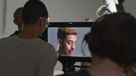 Actores-Con-Guiones-Ensayando-Mientras-Filman-Una-Película-O-Un-Video-En-Un-Estudio-Con-El-Equipo-De-Filmación-Y-Una-Directora-Mirando-Un-Monitor-En-El-Fondo.-1